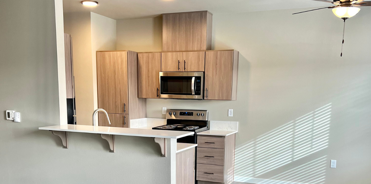 Modern kitchen with sleek wooden cabinets, stainless steel appliances, and a bright breakfast bar.