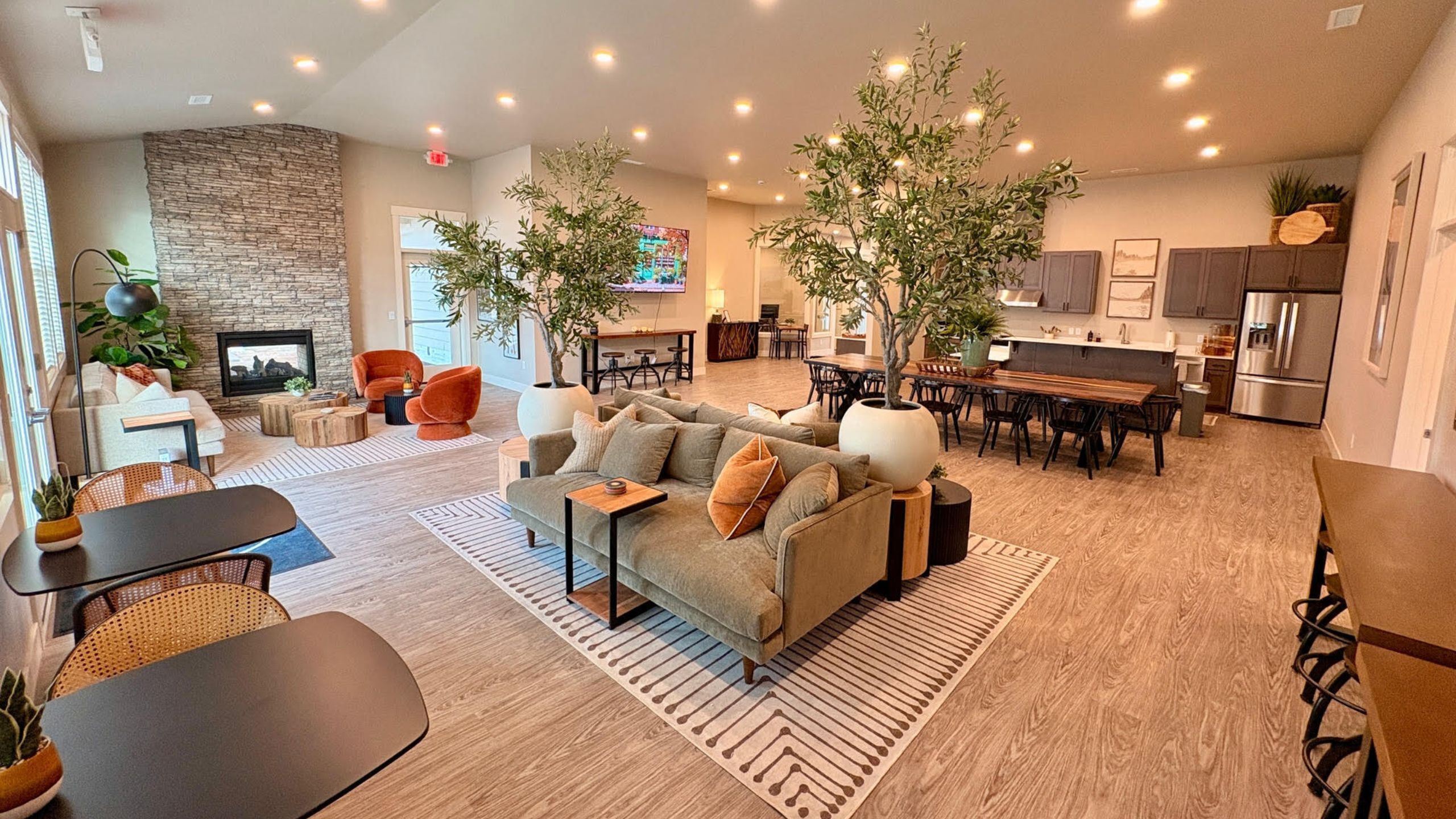 Elegant open-concept living room with modern seating, stone fireplace, and a stylish kitchen area, perfect for entertaining.