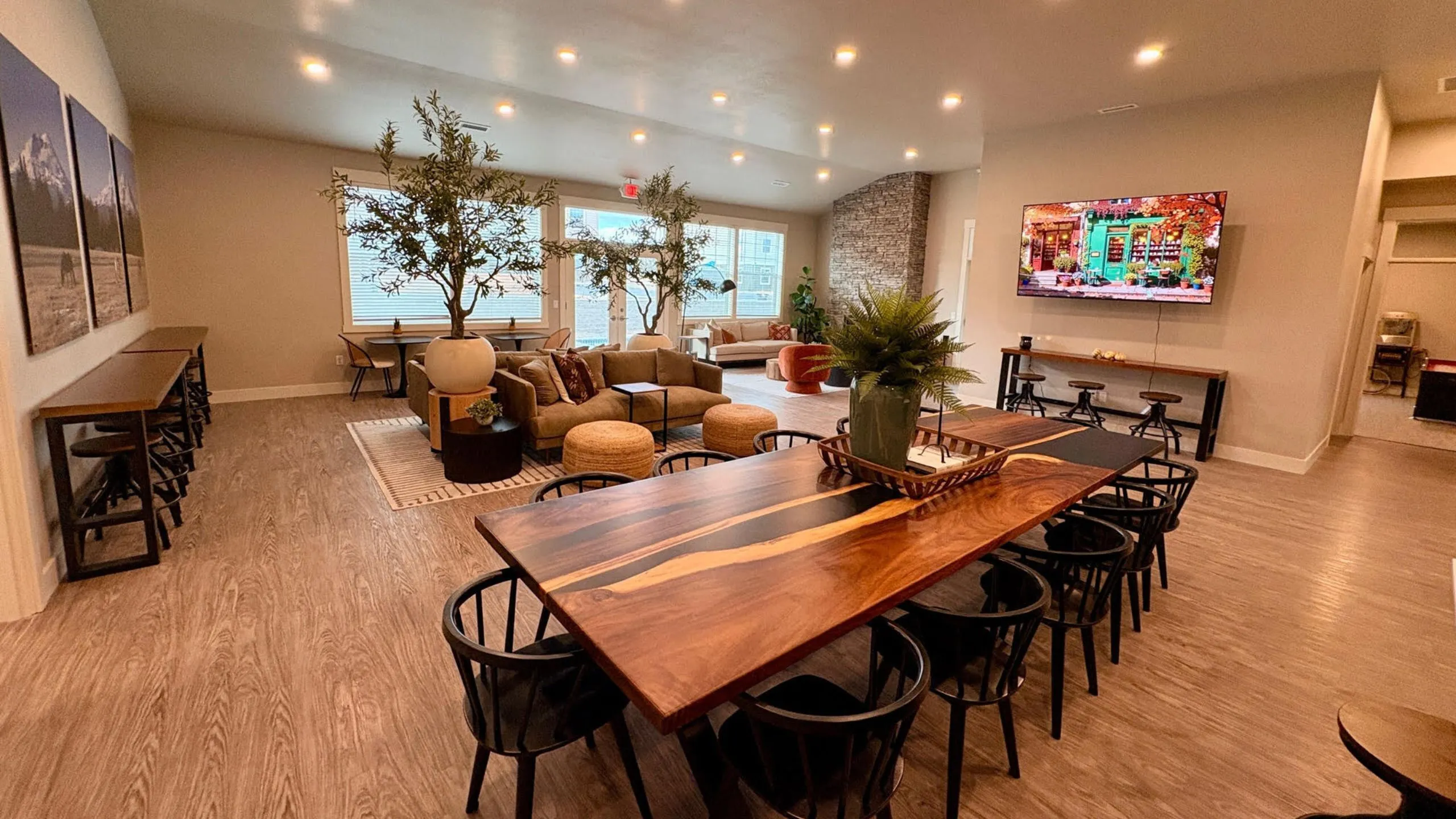 Spacious and inviting living area with modern decor showcasing a large wooden dining table, cozy seating, elegant lighting, and vibrant greenery.