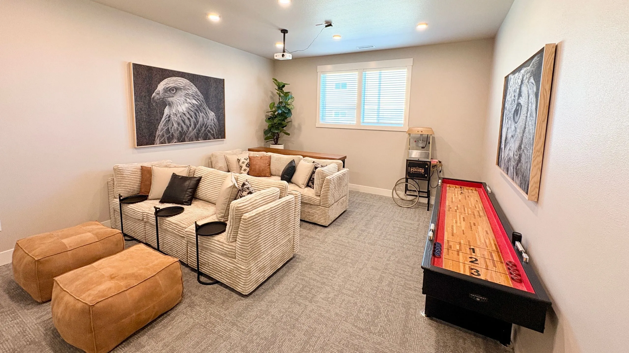 Modern entertainment room with cozy sofas, vibrant shuffleboard table, stylish animal artwork, and natural light for a welcoming atmosphere.