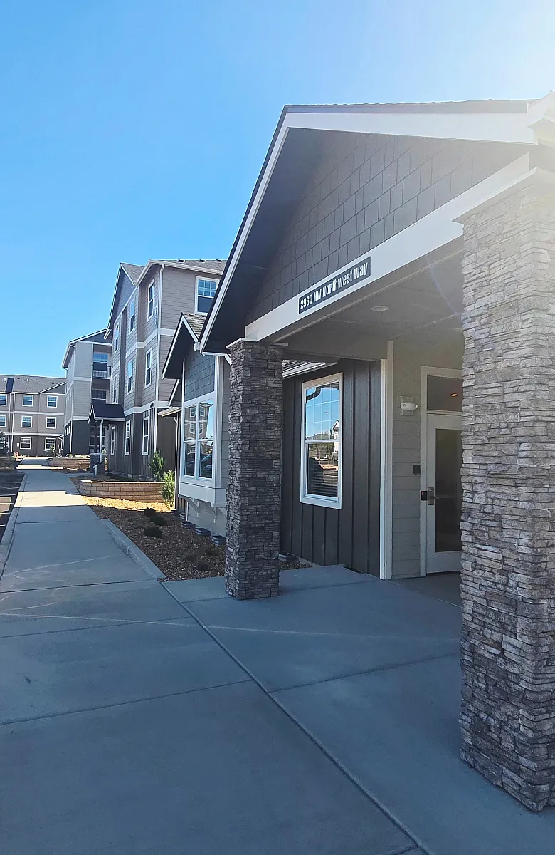 Modern apartment complex with stone accents and a welcoming entrance under clear blue skies.