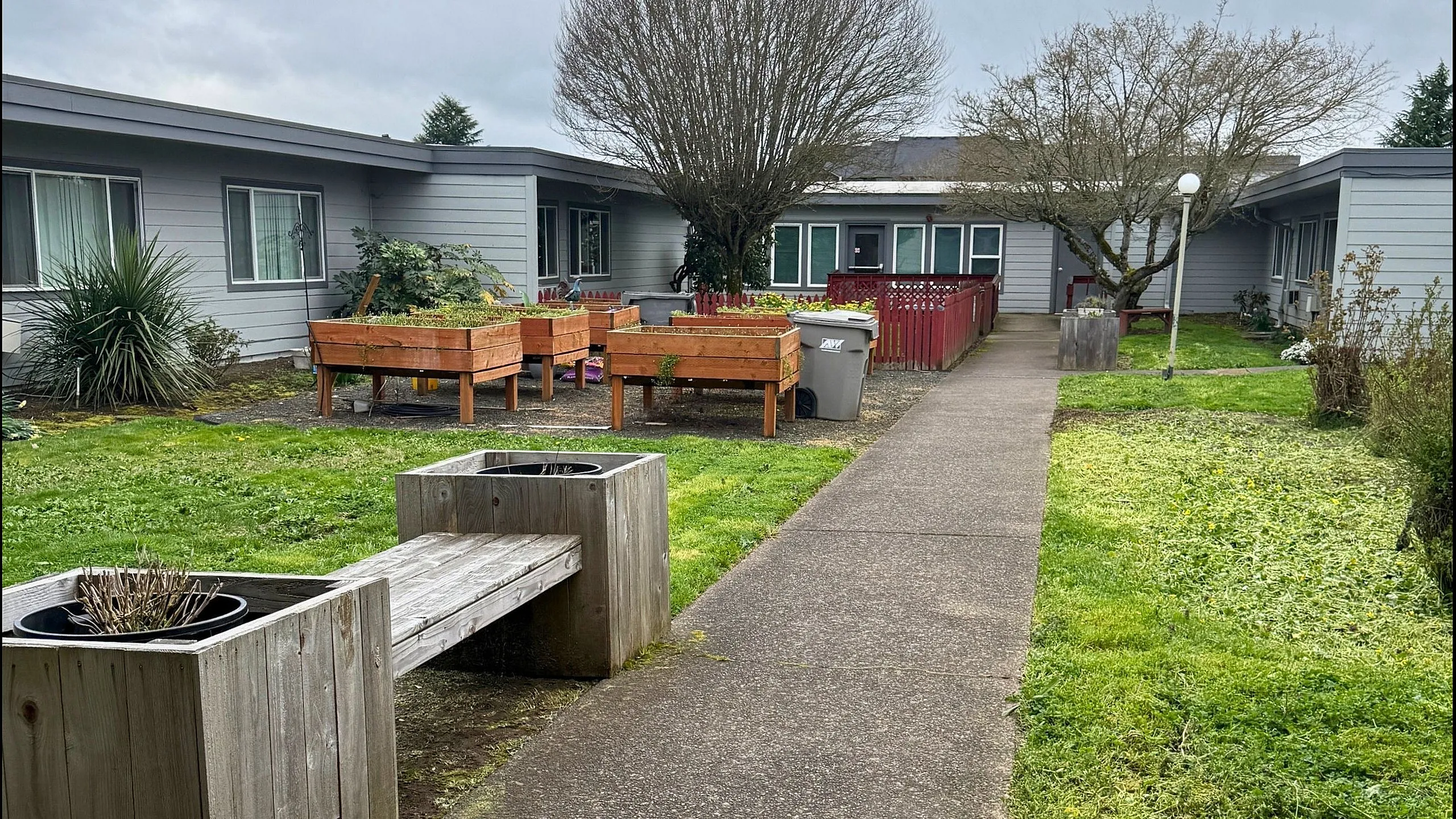 Charming apartment complex courtyard with vibrant raised garden beds, well-maintained greenery, and cozy outdoor seating area.