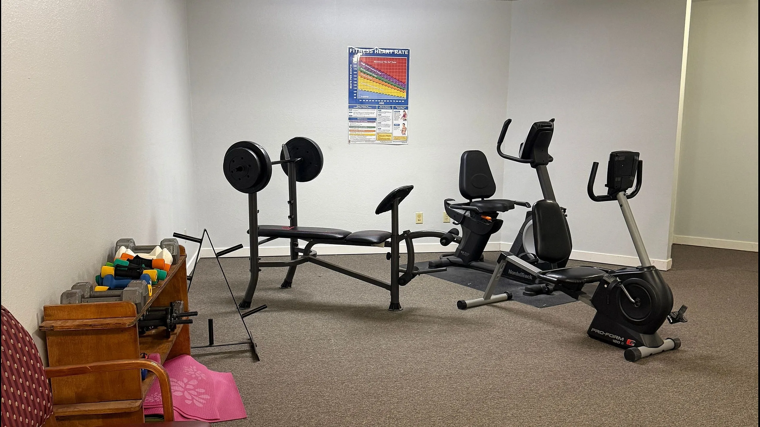 Inviting fitness room equipped with multi-use gym equipment, free weights, and exercise bike, perfect for a healthy lifestyle.