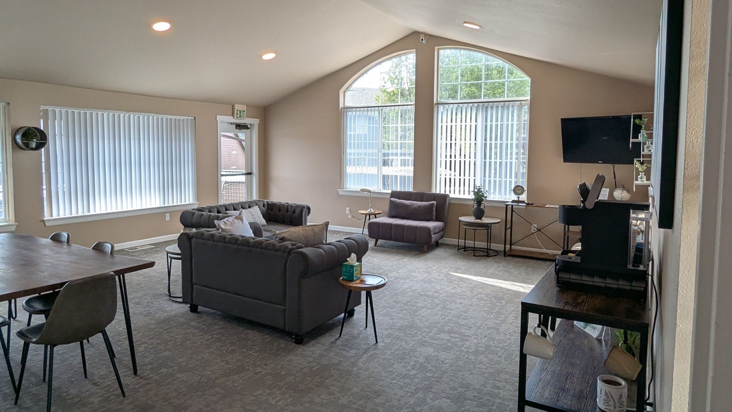 Bright and spacious living room with elegant sofas, large windows, and a cozy dining area, perfect for entertaining.