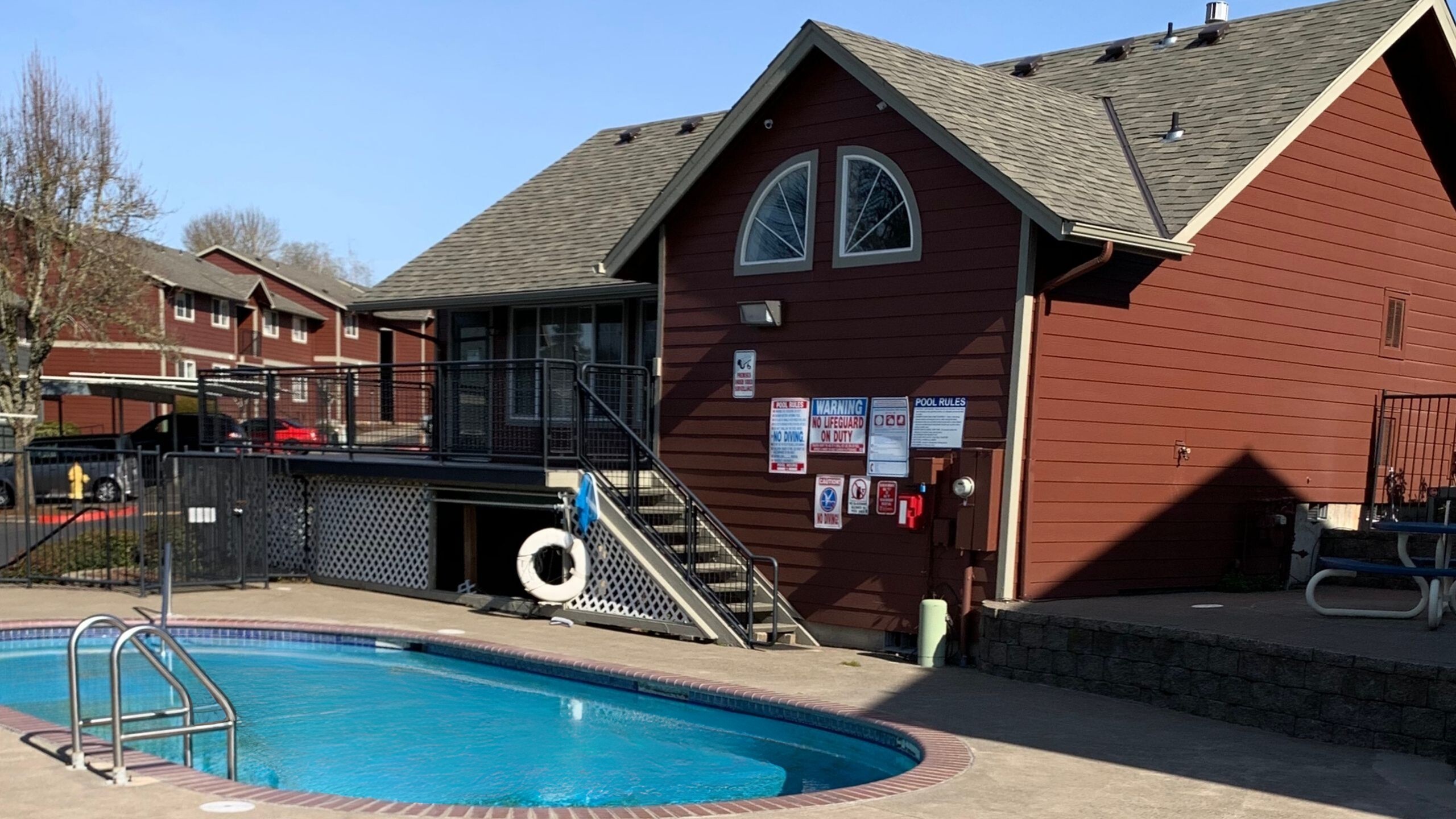 Inviting outdoor pool area adjacent to charming red brick building, ideal for leisure and relaxation.