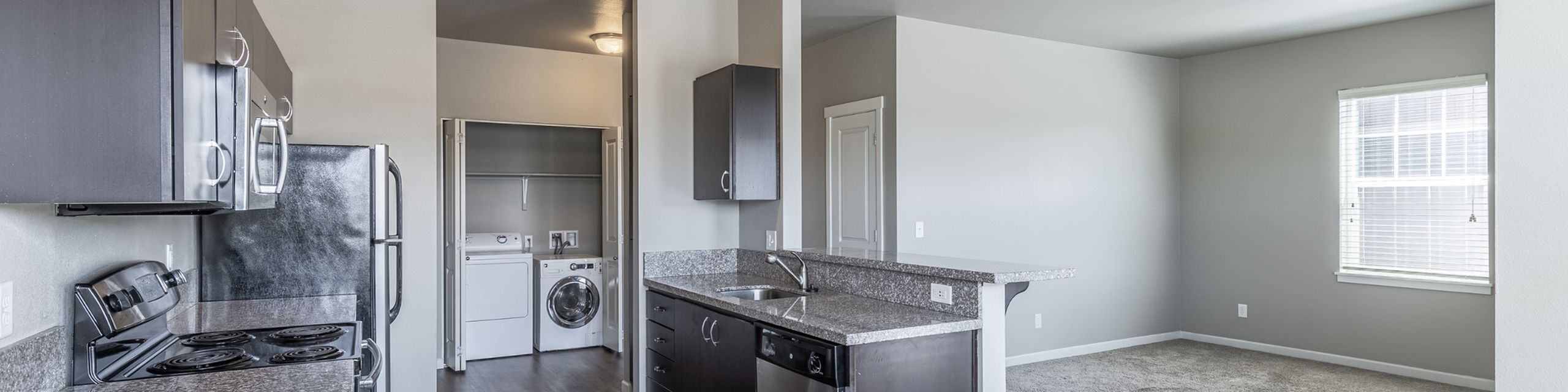Bright open-plan kitchen with sleek cabinets, modern appliances, and convenient in-unit laundry area, perfect for comfortable living.