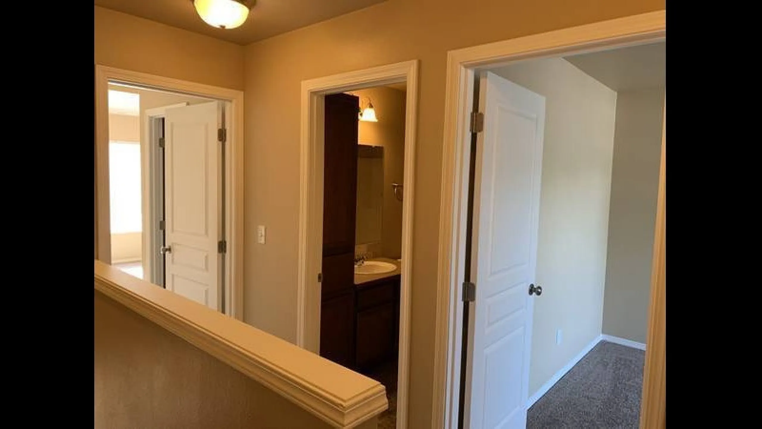 Bright and welcoming hallway with access to a modern bathroom and spacious bedrooms, featuring elegant white doors and warm lighting.