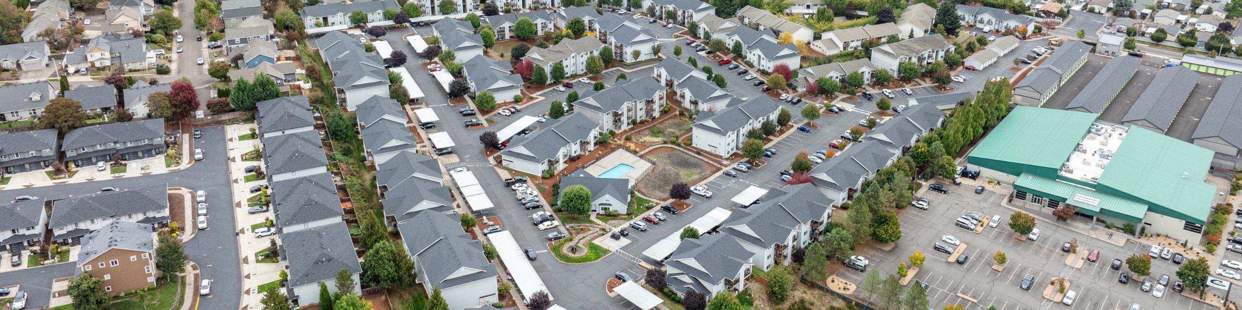 Expansive aerial view of a modern residential community featuring beautifully designed townhomes, lush green spaces, and a sparkling pool, ideal for comfortable living.