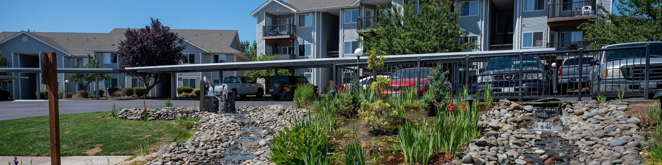 Charming residential apartment complex with well-maintained landscaping, featuring a serene rock garden and elegant water feature.