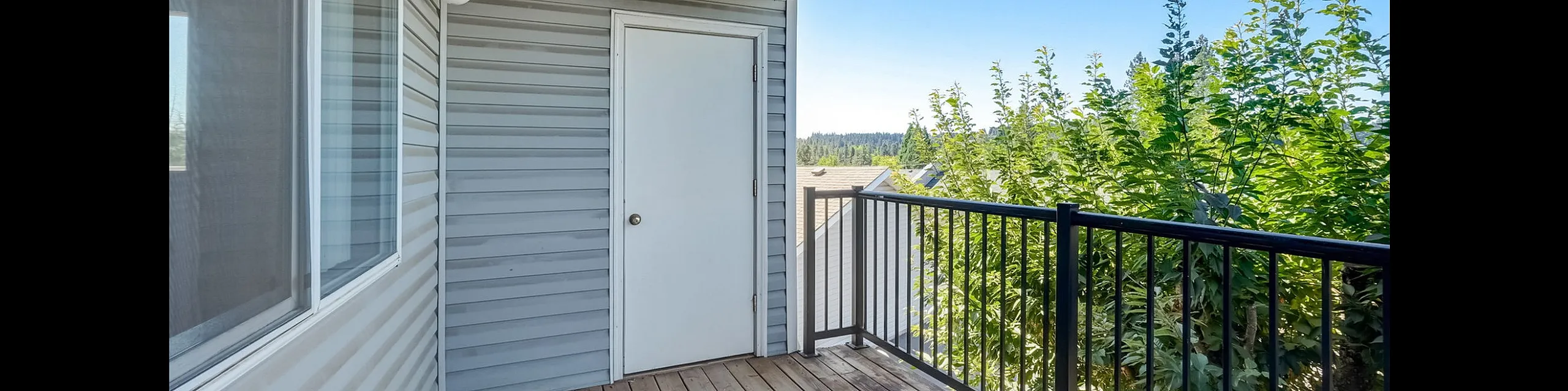 Charming wooden balcony with scenic tree-lined view, perfect for relaxation and outdoor enjoyment.