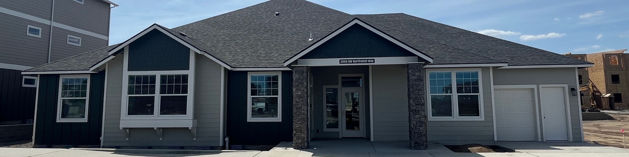 Charming single-story home with modern grey and dark siding, featuring a welcoming front porch and beautifully framed windows.