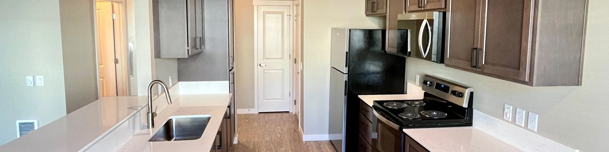 Modern kitchen with sleek dark cabinetry, elegant countertops, and stainless steel appliances, offering a stylish and functional cooking space.
