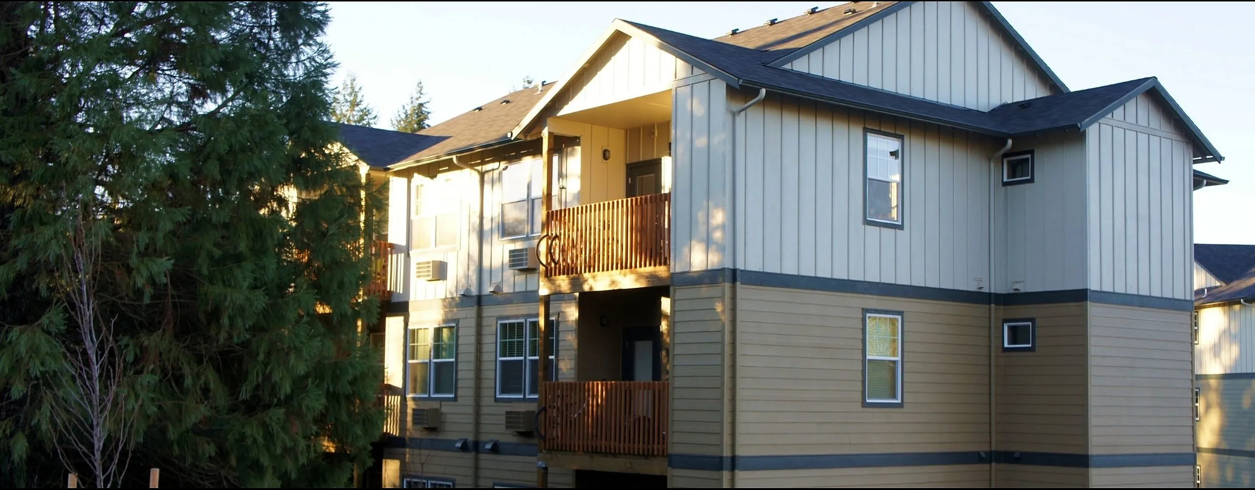 Charming two-story apartment building with wooden balconies nestled among lush greenery, perfect for serene living.