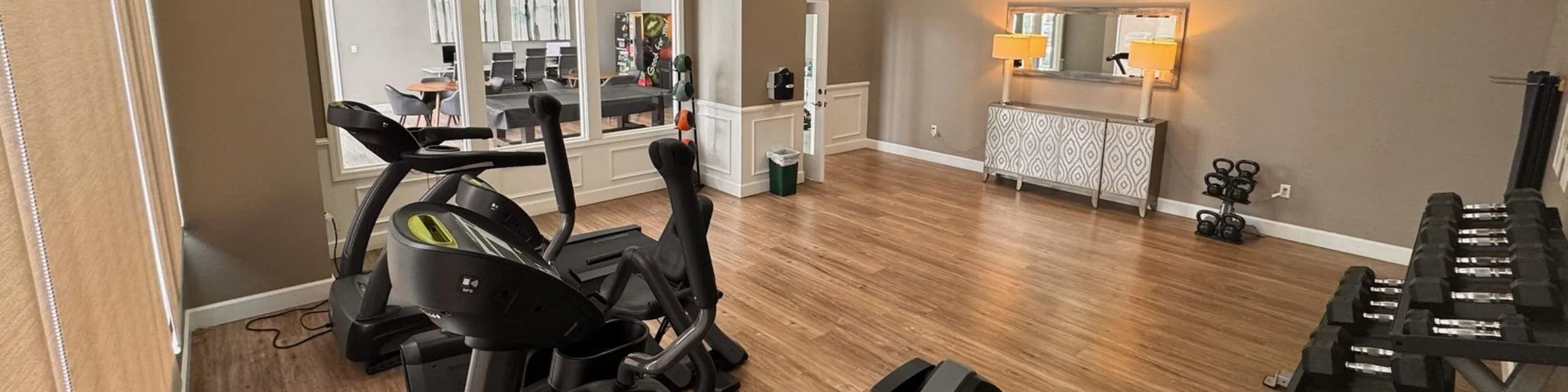 Spacious home gym with modern cardio equipment and free weights, perfect for fitness enthusiasts.
