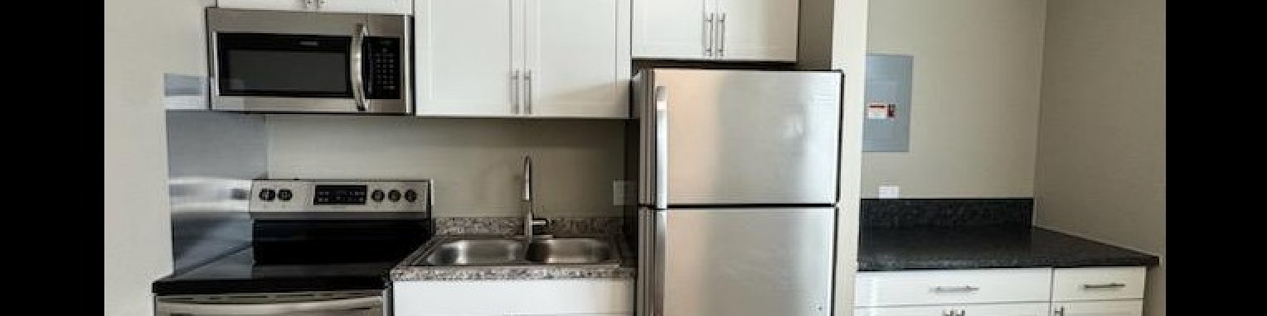 Modern kitchen with sleek stainless steel appliances, elegant white cabinetry, and stylish laminate flooring.