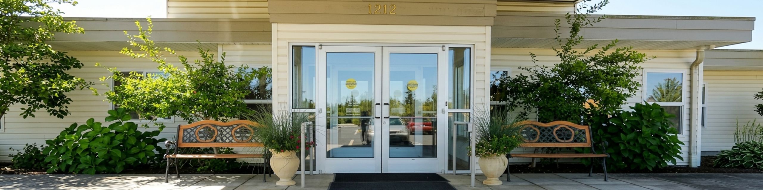 Inviting apartment entrance with elegant benches and lush greenery, creating a welcoming curb appeal.