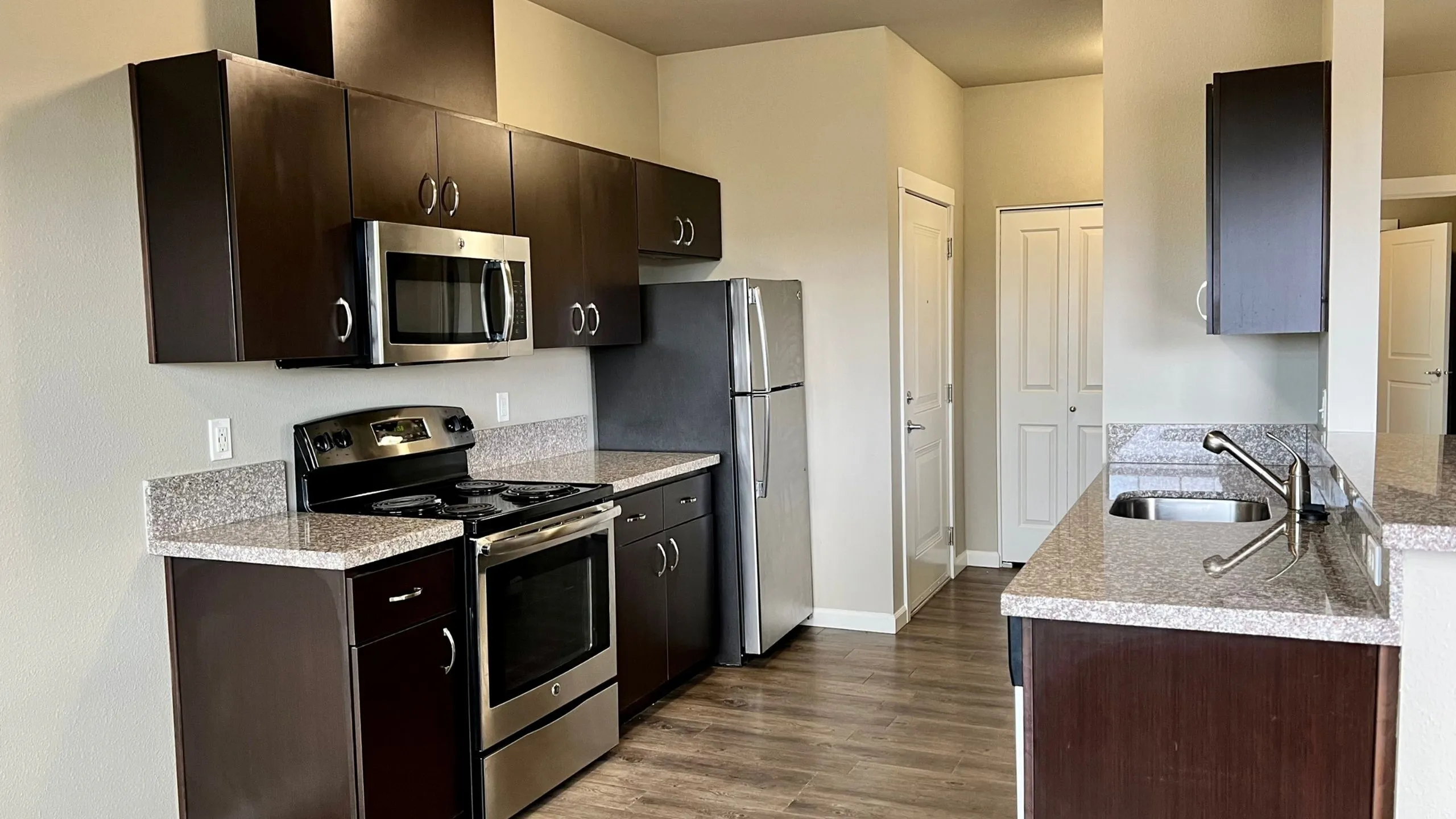 Sleek modern kitchen with stainless steel appliances, dark cabinetry, and granite countertops, offering a sophisticated and functional cooking space.