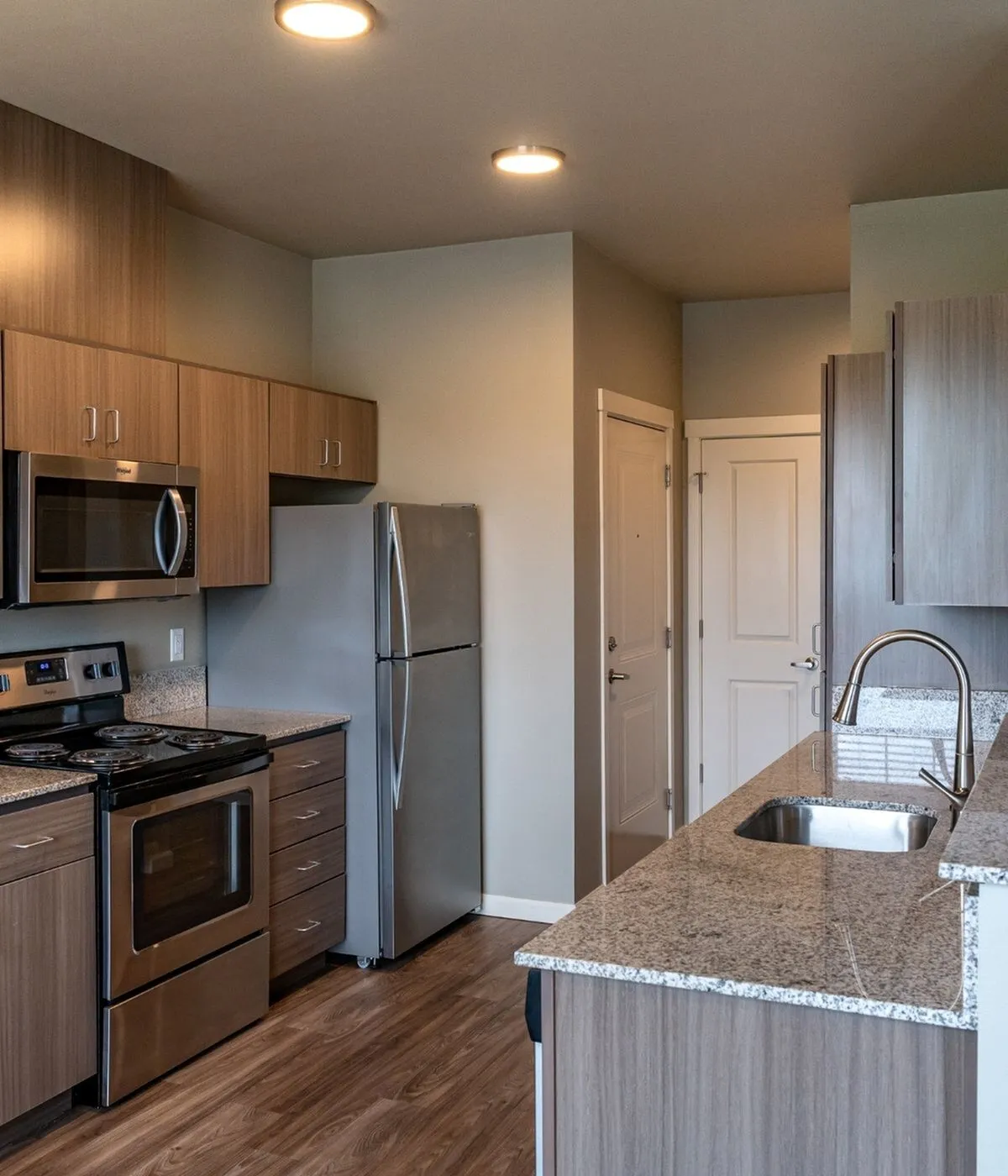 Modern kitchen with sleek stainless steel appliances, elegant wood cabinetry, and a stylish granite countertop for a contemporary feel.