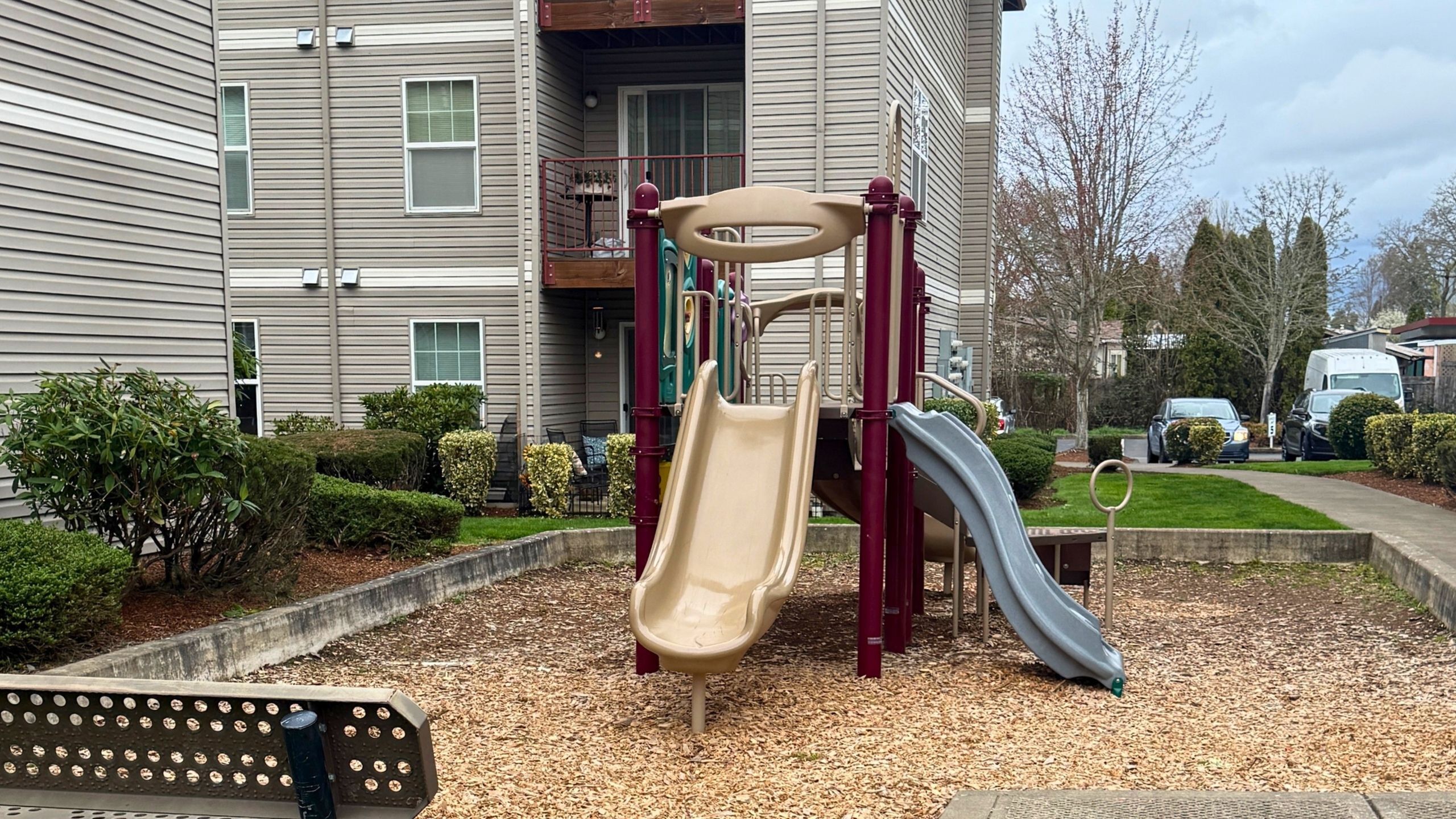 Inviting playground area in an apartment complex, featuring slides and lush landscaping for family-friendly living.
