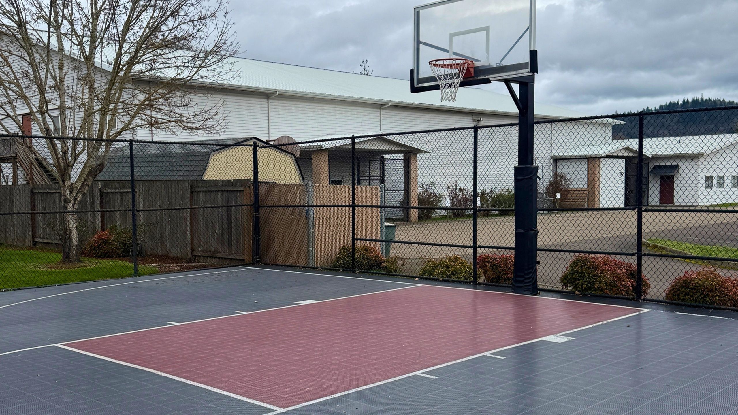 Inviting outdoor basketball court with fenced perimeter, perfect for sports enthusiasts and community events.