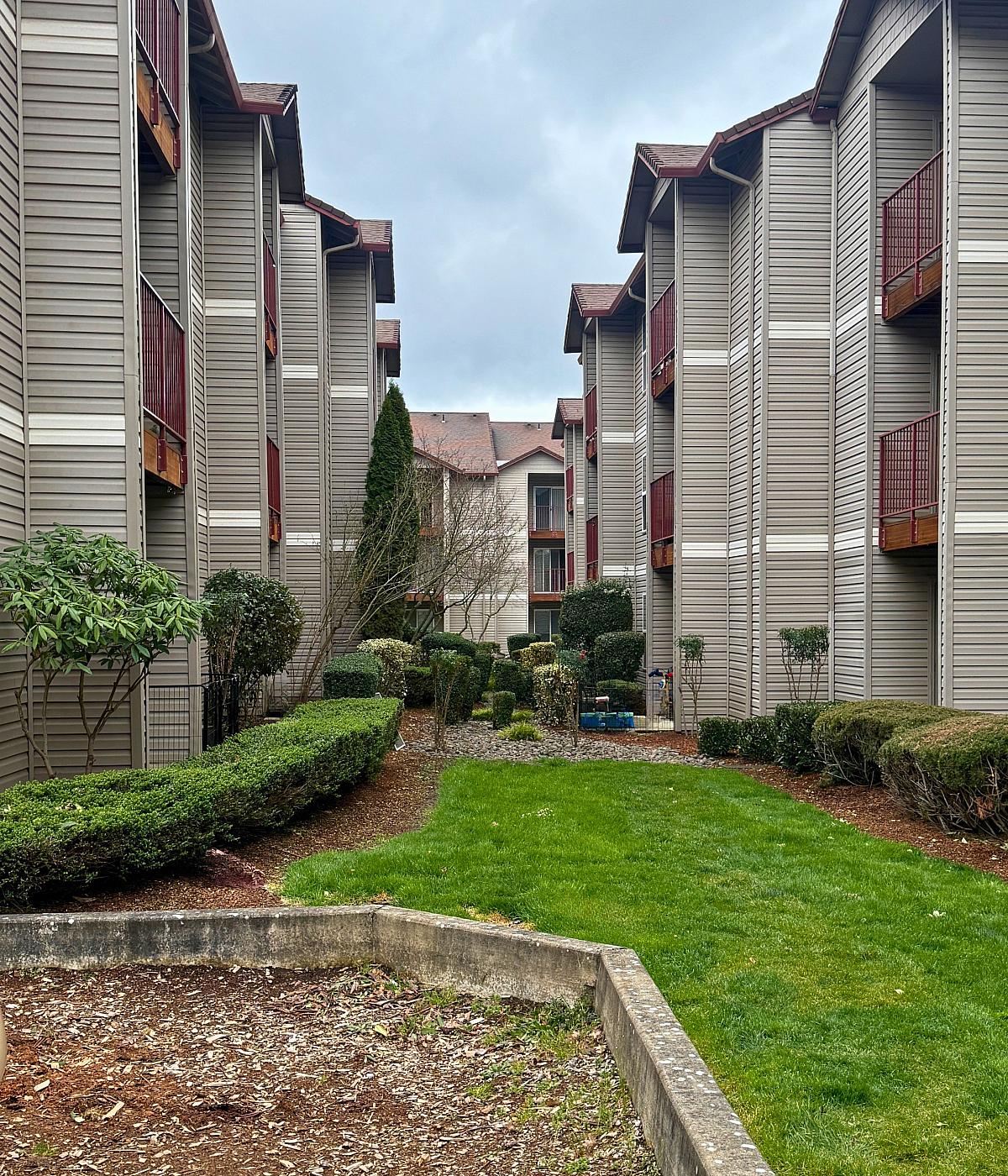Modern apartment complex exterior with lush green landscaping and unique architectural design.