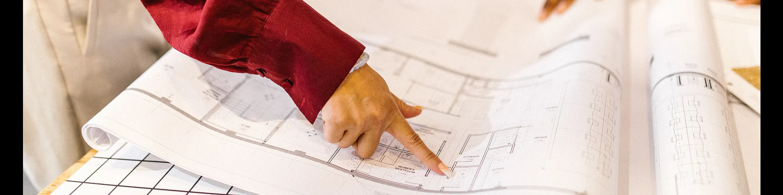 Close-up of professionals reviewing a detailed architectural floor plan, highlighting spacious and innovative apartment layouts.