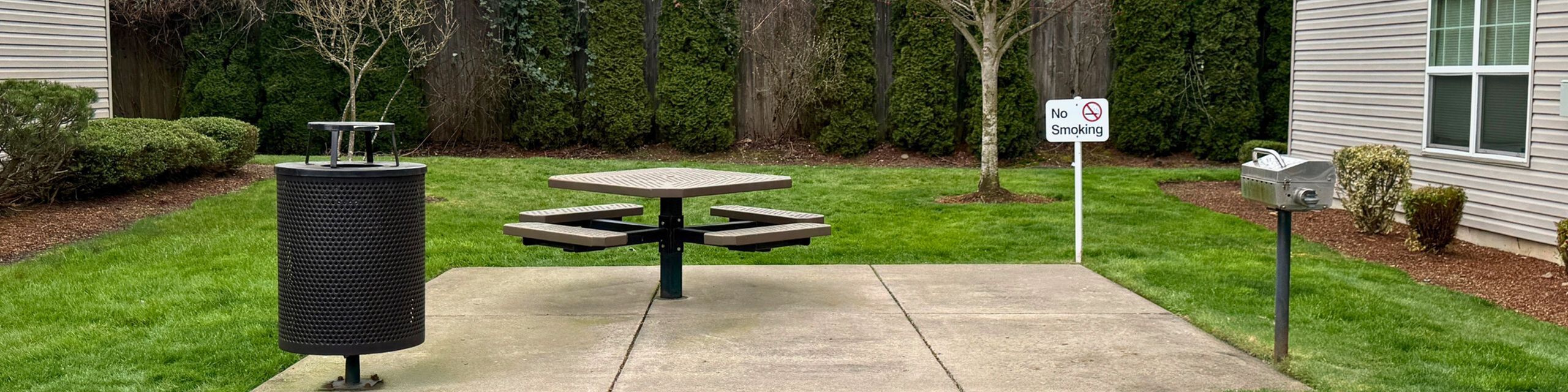 Charming outdoor area with a picnic table, grill, and lush green surroundings, perfect for relaxation and gatherings.