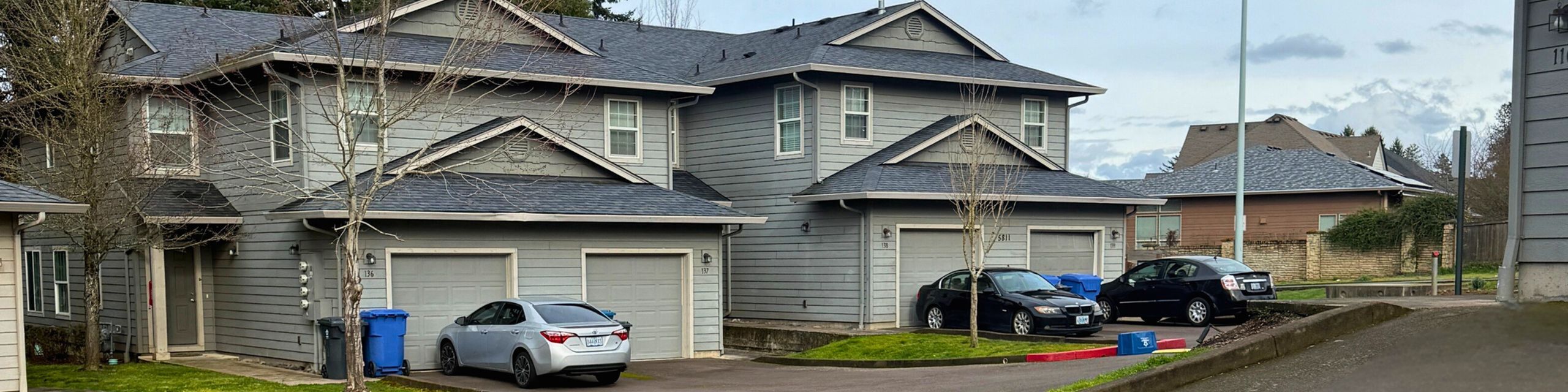 Charming duplex with modern exterior, featuring two-car garages, nestled in a serene suburban neighborhood.