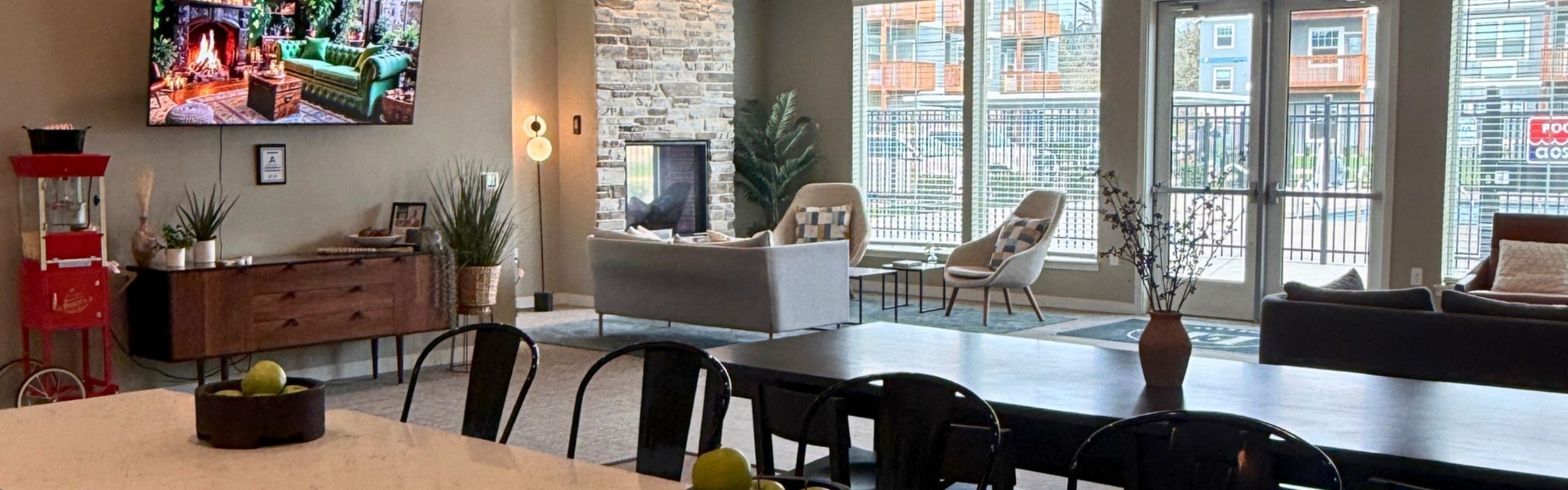 Chic apartment lounge with elegant stone fireplace, cozy seating, and natural light streaming through large windows.