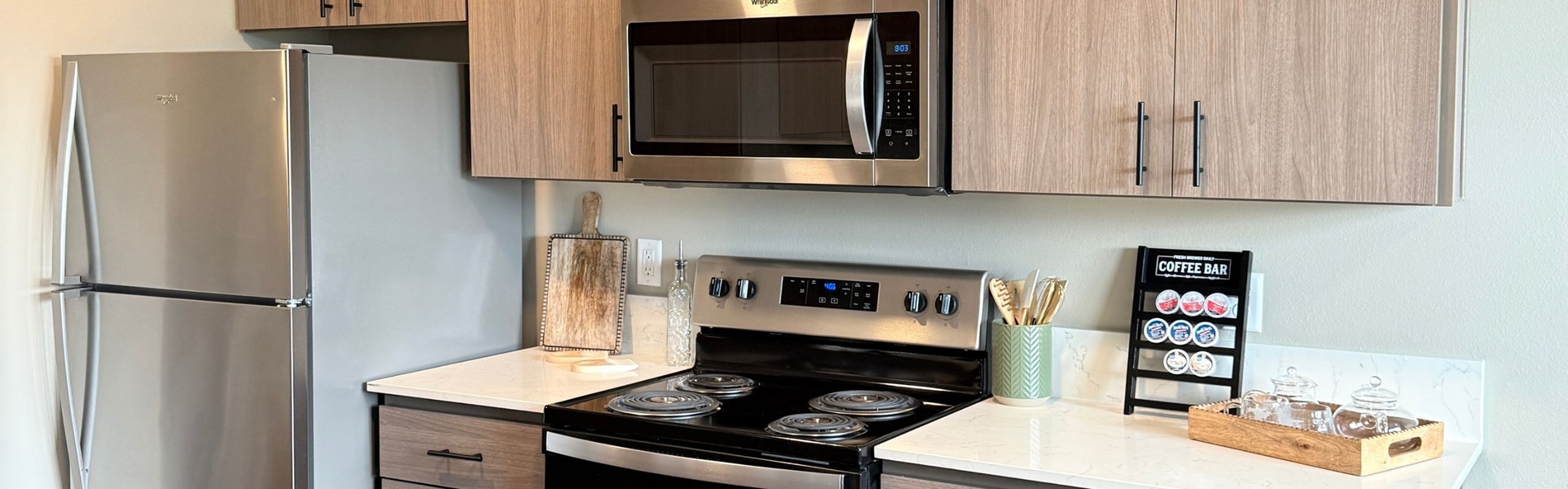 Sleek modern kitchen with stainless steel appliances, wooden cabinetry, and stylish countertop coffee bar.