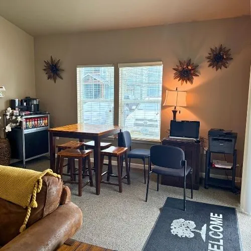Cozy apartment corner with a warm leather sofa, stylish coffee bar, and functional workspace under natural light.