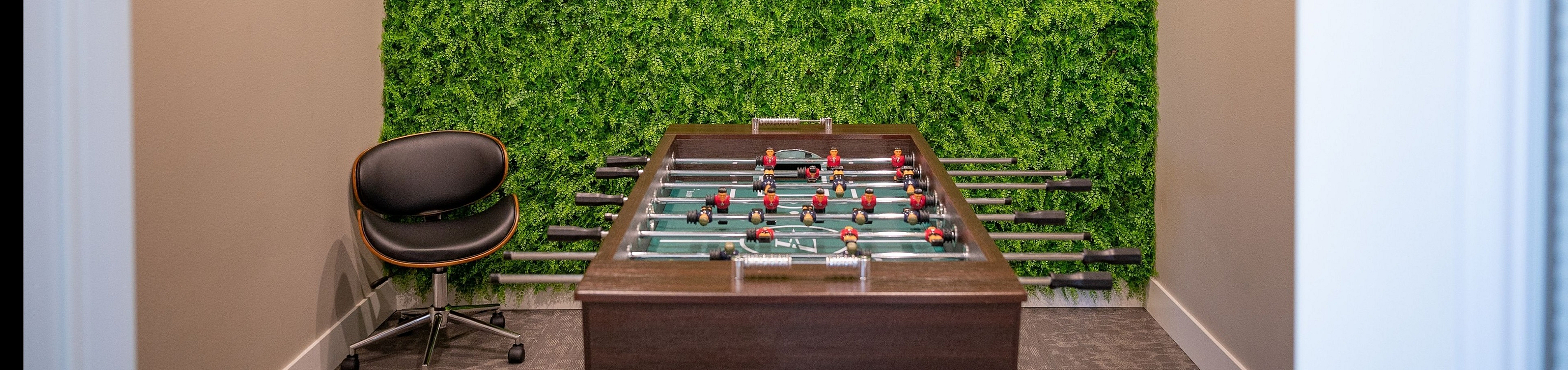 Chic recreation nook featuring a foosball table with vibrant green accent wall, ideal for entertainment and relaxation.