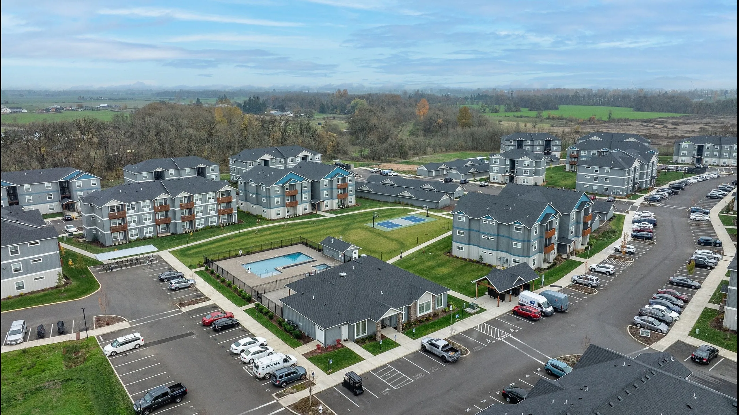 Charming apartment complex surrounded by lush greenery, featuring spacious units with private balconies, a sparkling swimming pool, ample parking, and recreational areas.