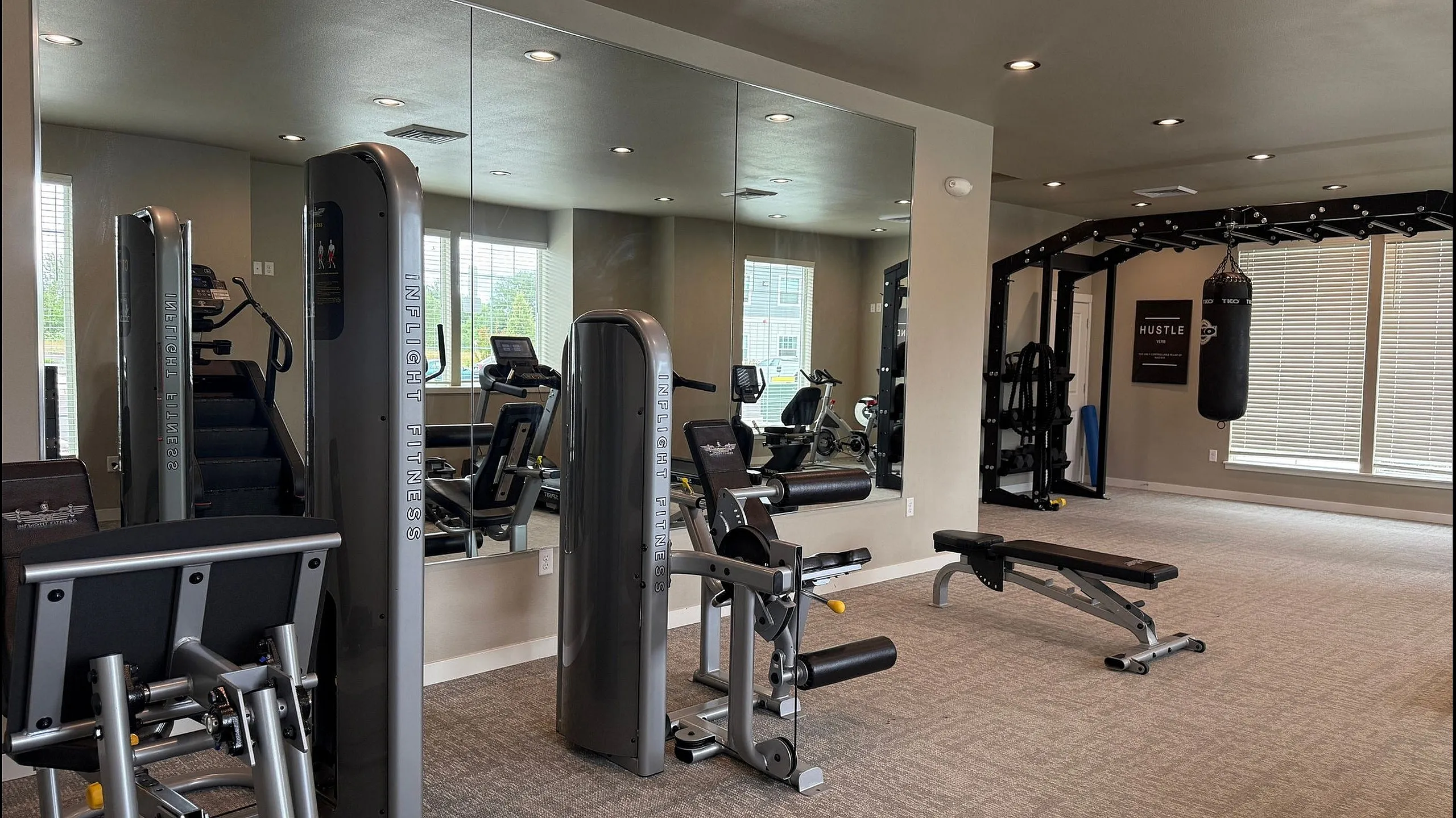 Contemporary fitness center with state-of-the-art equipment, mirrored walls, and natural light offering an ideal workout environment.