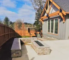 Charming backyard with a cozy stone fire pit, surrounded by scenic views and modern architectural design.