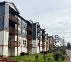 Modern apartment complex with charming balconies, surrounded by lush greenery and a well-maintained walkway.