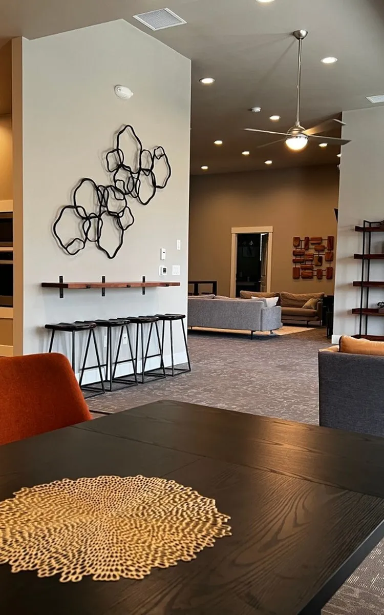 Contemporary apartment interior featuring sleek decor with a geometric wall art, stylish bar stools, and a cozy lounge area.