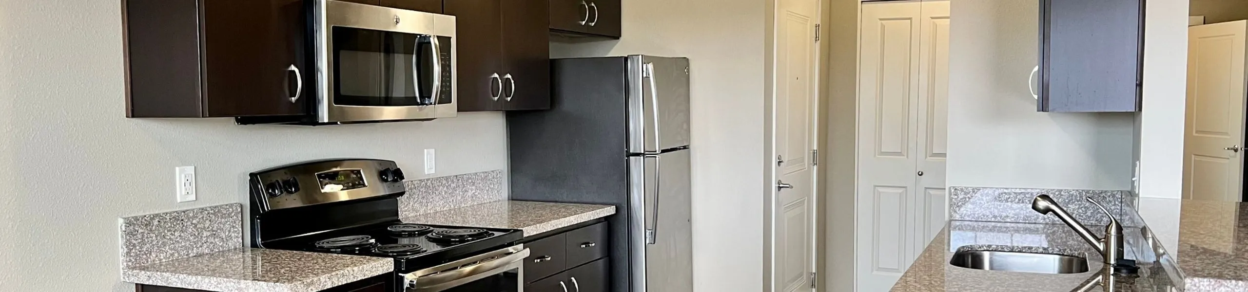 Modern kitchen with sleek stainless steel appliances, elegant granite countertops, and stylish dark cabinetry.