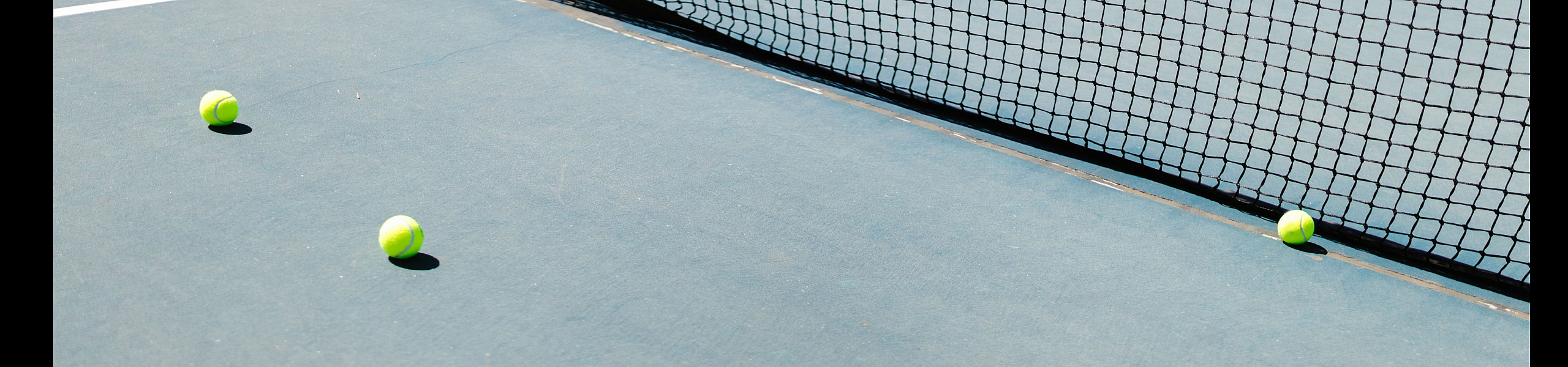 Inviting tennis court with bright tennis balls adding a splash of color, ideal for a sporty lifestyle.