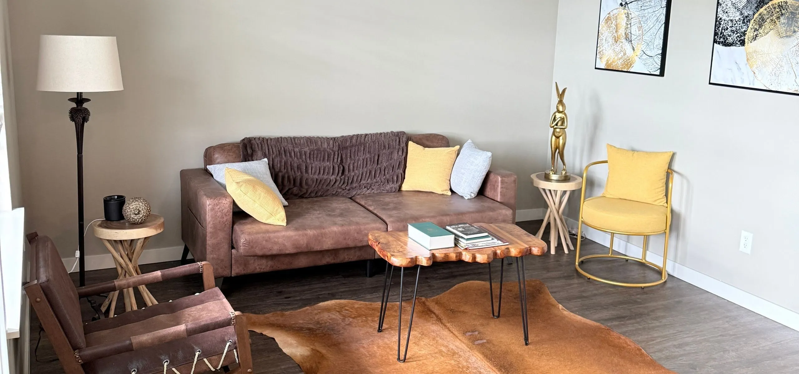 Chic living room with a cozy brown sofa, accented with soft pillows, a wooden coffee table, and stylish art pieces, creating a warm and inviting atmosphere.