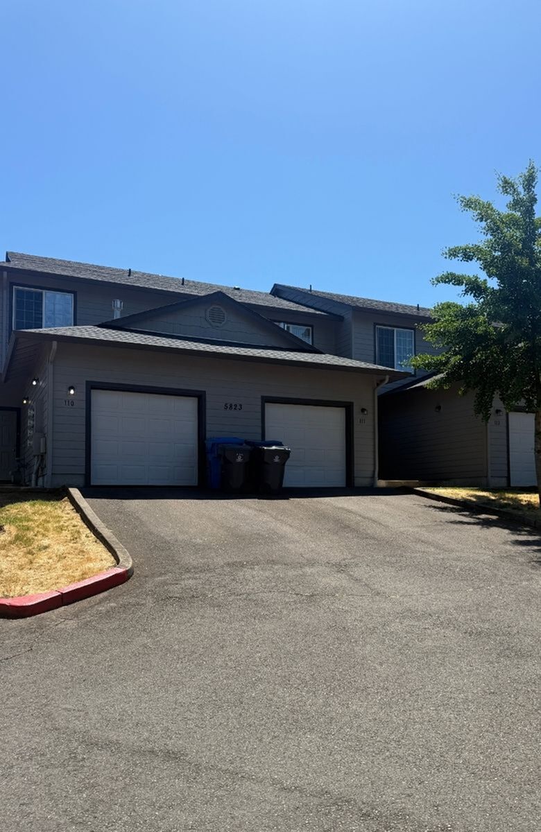 Inviting duplex with modern architecture, featuring twin garages and a well-maintained exterior, set against a clear blue sky.