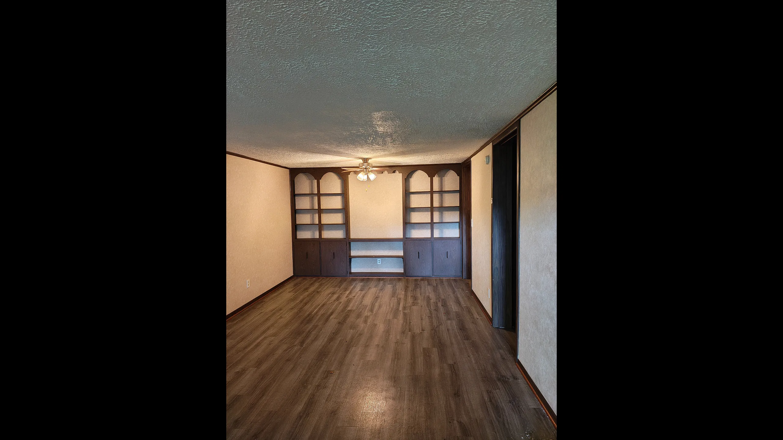 Elegant living space featuring vinyl flooring, built-in shelving, and a ceiling fan for a cozy and functional area.