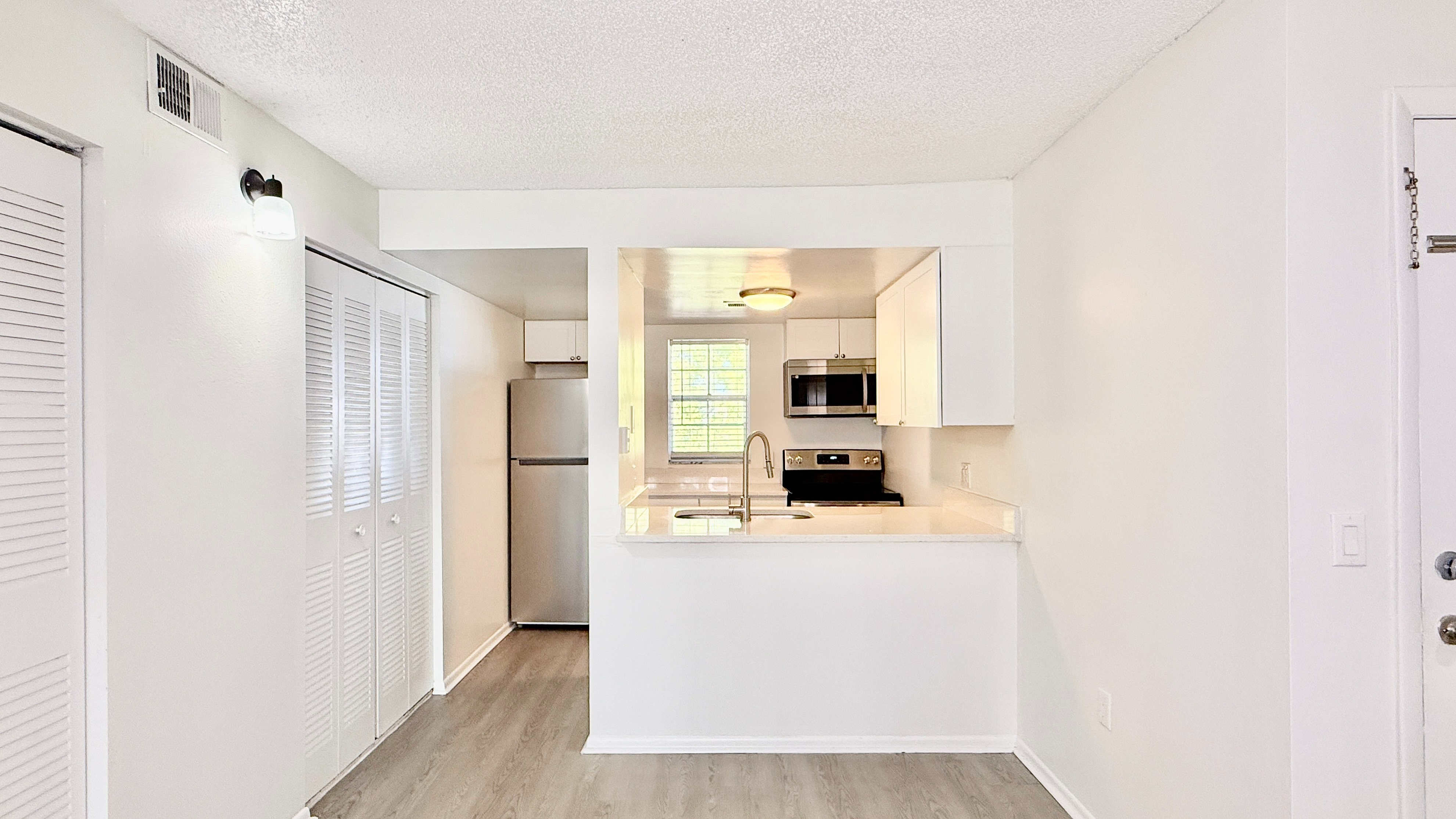 Modern kitchen with stainless steel appliances, sleek countertops, and an open-plan design in a bright apartment.