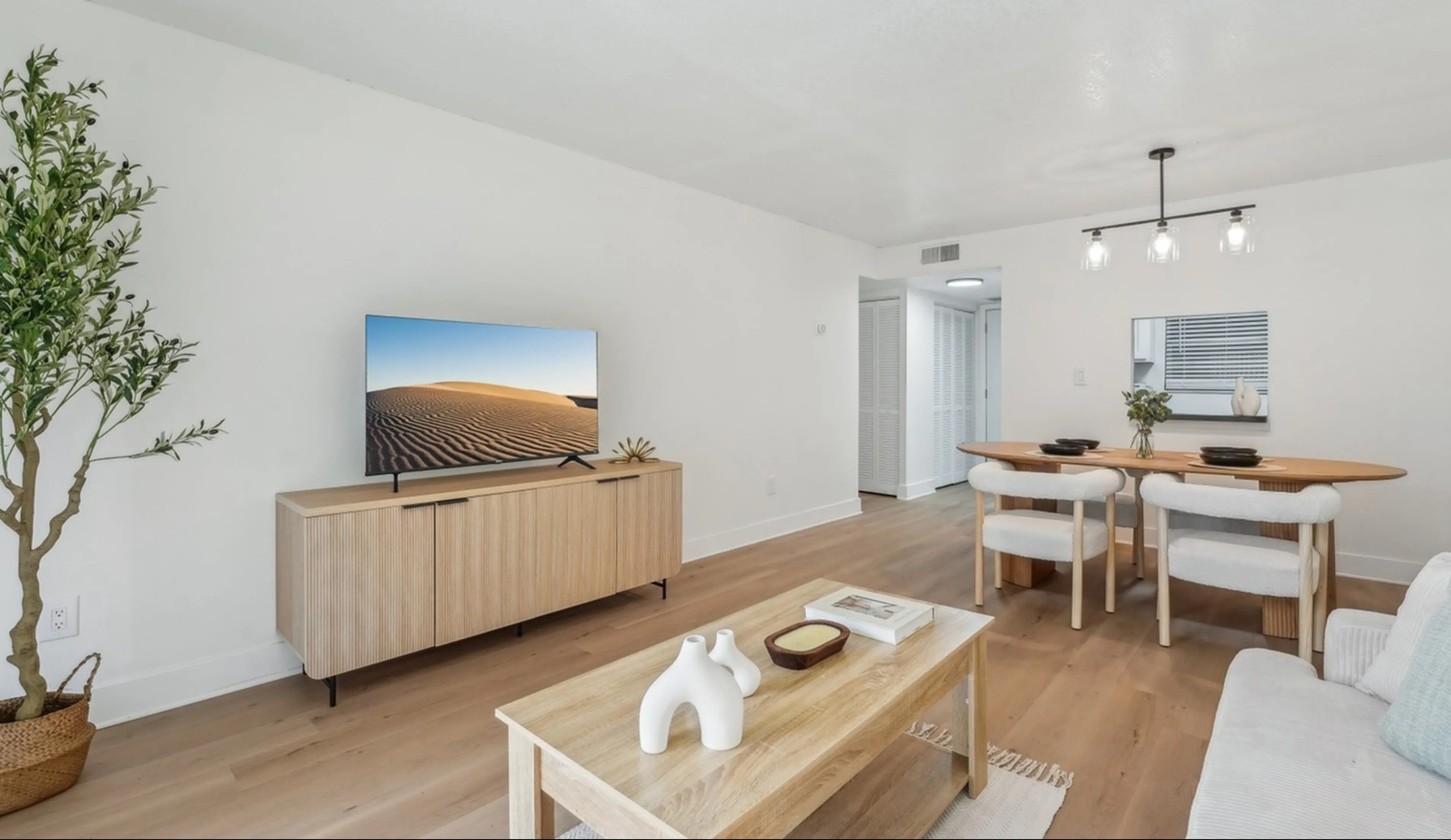 Bright and modern living room with sleek wooden floors, elegant dining area, and minimalist decor, perfect for stylish entertaining.