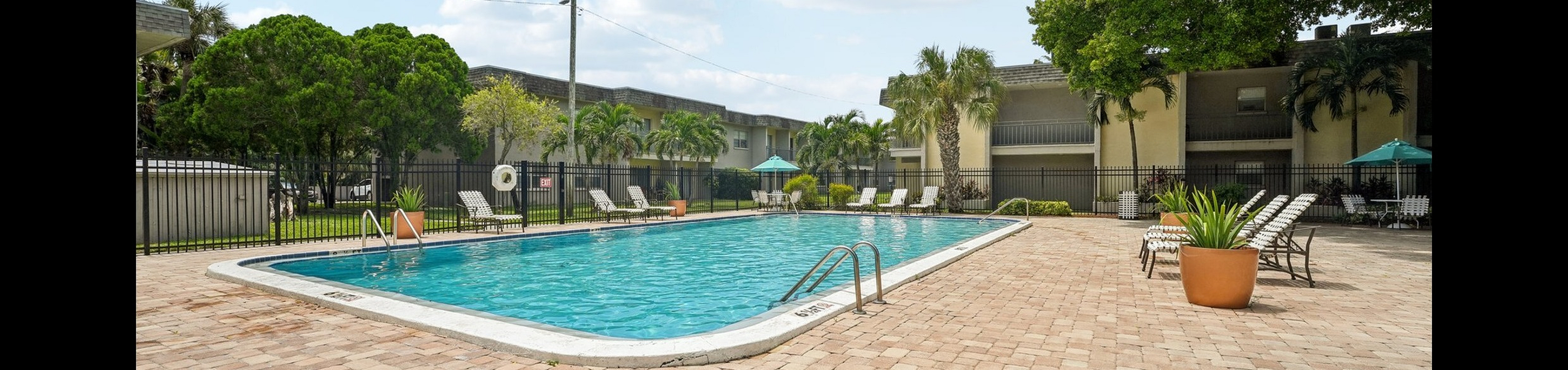 Inviting residential pool area surrounded by lush greenery, sun loungers, and cozy seating, perfect for relaxation and leisure.