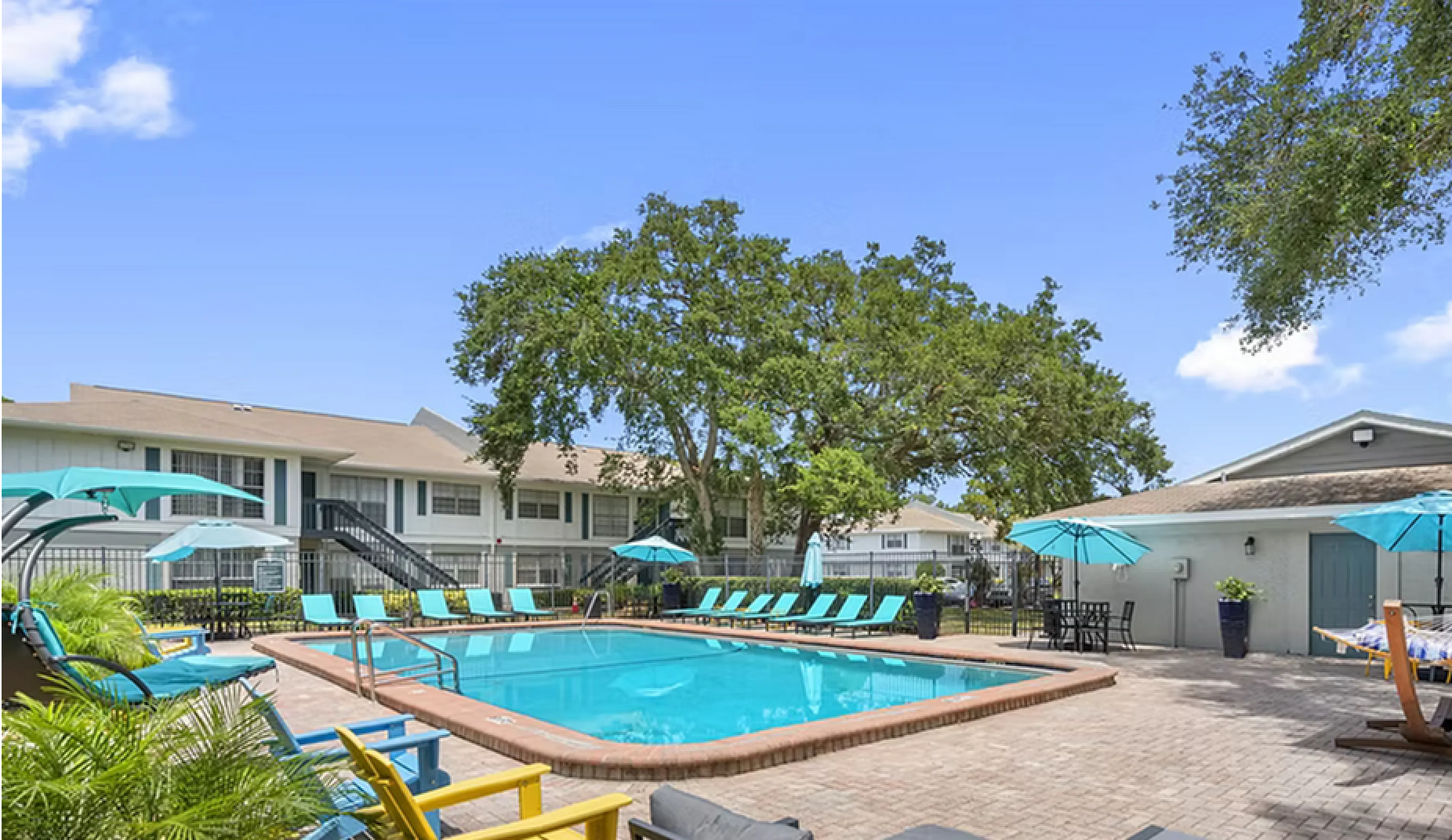 Inviting community pool area with vibrant seating, poolside loungers, shaded hammocks, and lush landscaping.