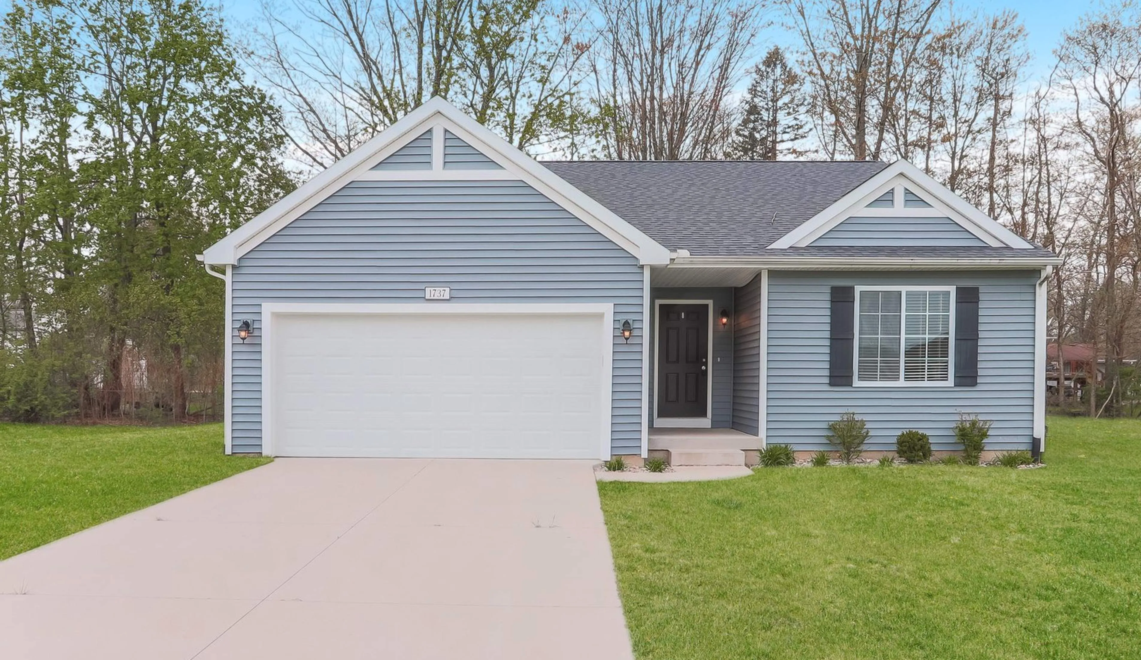 Charming suburban home with elegant blue siding, spacious two-car garage, and lush green lawn.