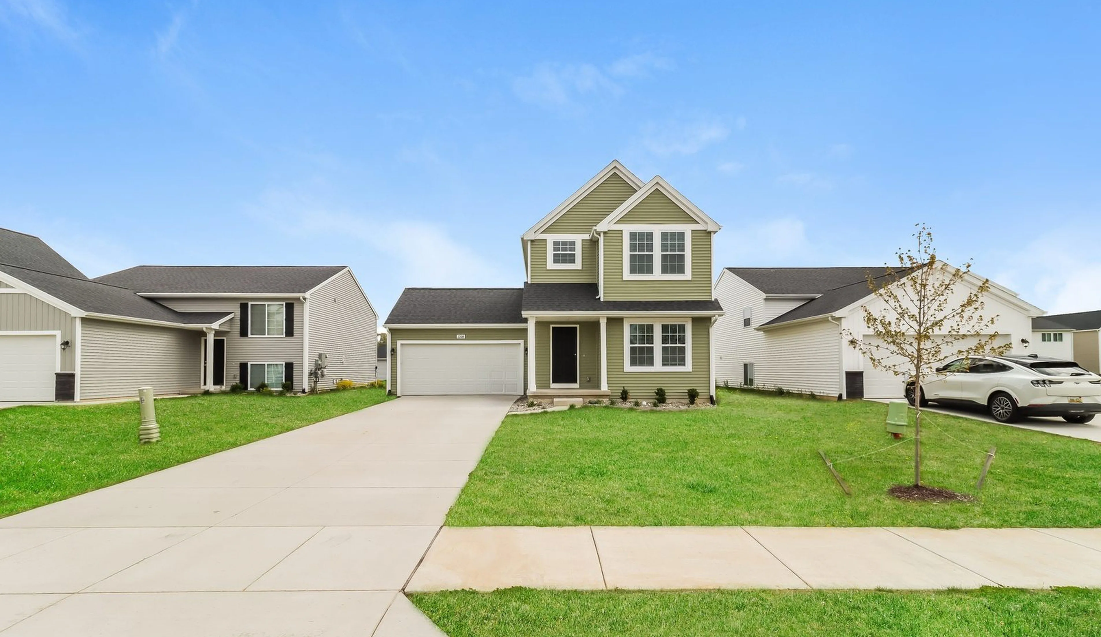 Charming two-story suburban home with a welcoming green lawn and attached garage, set in a peaceful neighborhood.