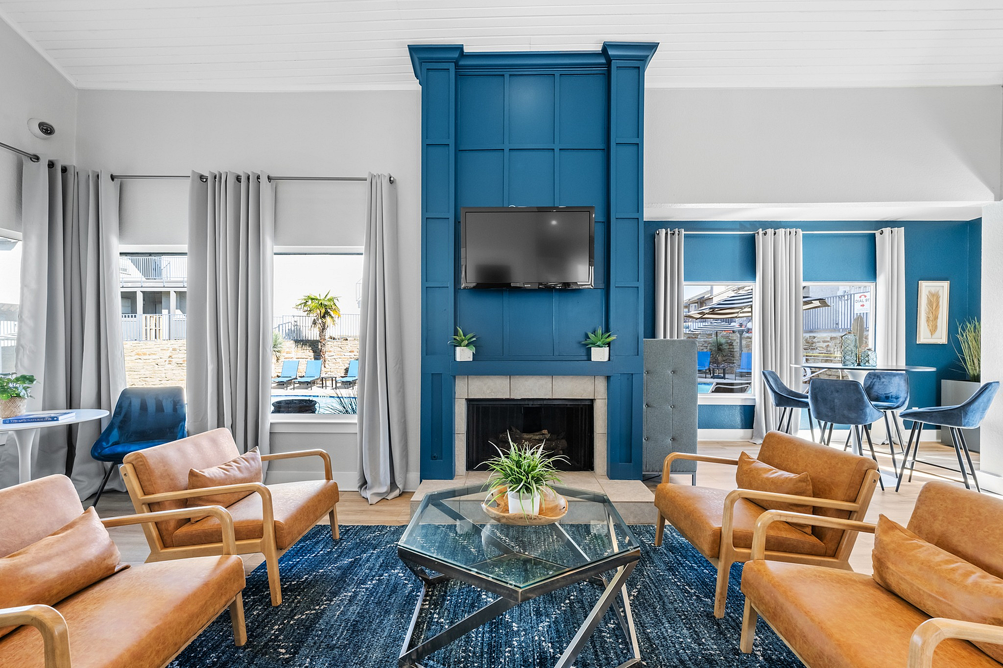 Chic living room with modern blue accents, cozy fireplace, and elegant seating area. Sunlit dining nook with stylish decor, ideal for entertaining.