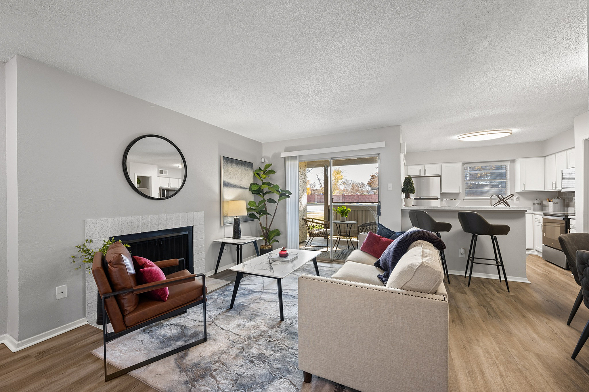 Charming living room with modern decor, cozy seating, and natural light leading to a sleek kitchen and stylish balcony.